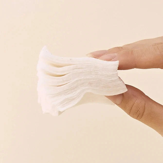 Heveblue cotton pad soaked in toner held flat against skin as spot mask